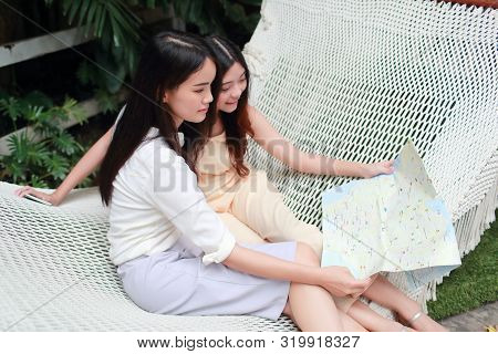 Young And Cute Asian Women Lying In A Hammock And Searching Location In A Map During Holiday