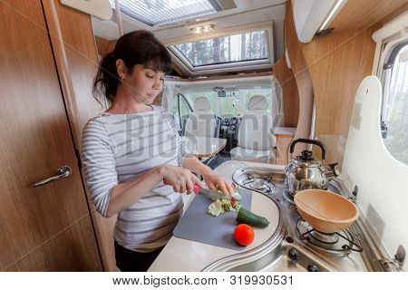 Woman cooking in camper, motorhome RV interior. Family vacation travel, holiday trip in motorhome, Caravan car Vacation.