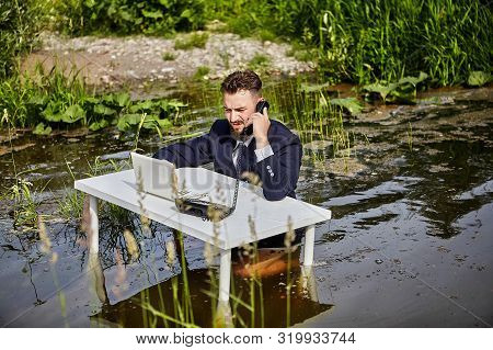 An Office Worker, A White Collar Worker, Or A Businessman Dressed In A Suit, Sits At A White Desk, T