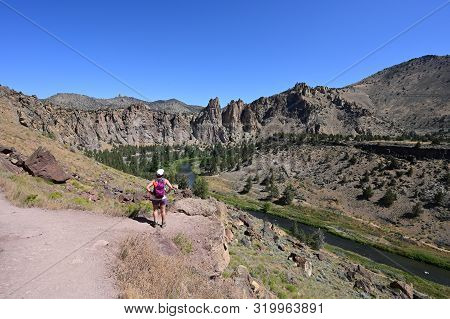 Young Woman On Misery Ridge Trail In Smith Rock State Park Near Terrebonne, Oregon On A Coudless Sum