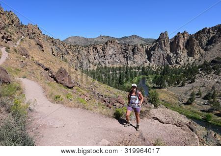 Young Woman On Misery Ridge Trail In Smith Rock State Park Near Terrebonne, Oregon On A Coudless Sum