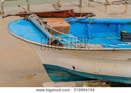 Closeup Of Fore Section Of Blue And White Fishing Boat On Concrete Pier On Rainy Morning.