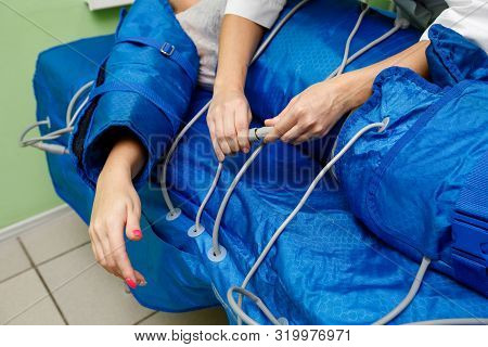 Woman In Pressotherapy Suit Lying Down Having Pressure Therapy For Weight Loss In Spa Salon