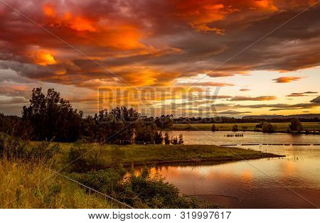 Beautiful Sunset Sky Over Rural Lakes With Blue Mountains In Far Distance.