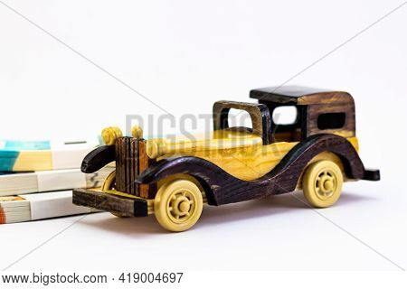 Close Up Shot Of A Wooden Vintage Car Toy With Money Notes Behind, Showing Rich Concept