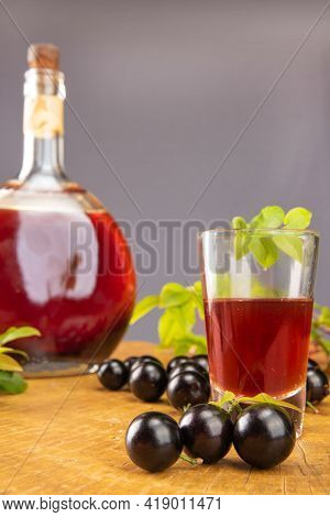 Jaboticaba, Bottle And Glass Of Homemade Brazilian Jaboticaba Liqueur On Wood With Leaves And Branch
