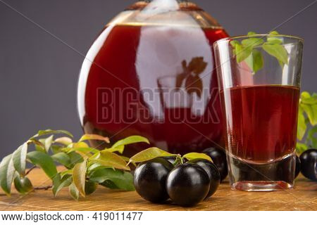 Jaboticaba, Bottle And Glass Of Homemade Brazilian Jaboticaba Liqueur On Wood With Leaves And Branch