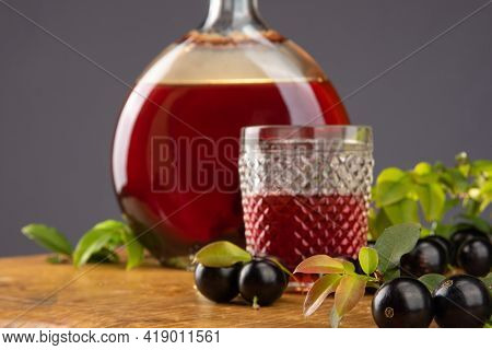 Jaboticaba, Bottle And Glass Of Homemade Brazilian Jaboticaba Liqueur On Wood With Leaves And Branch