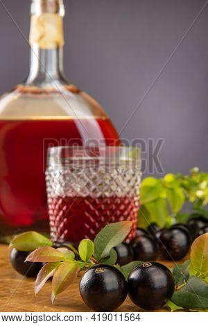 Jaboticaba, Bottle And Glass Of Homemade Brazilian Jaboticaba Liqueur On Wood With Leaves And Branch