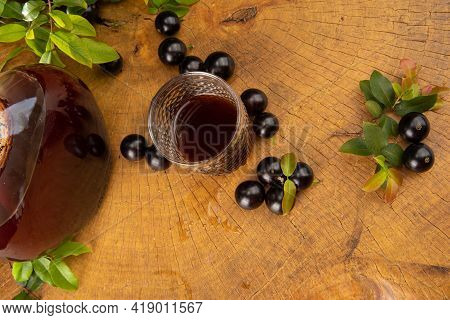 Jaboticaba, Bottle And Glass Of Homemade Brazilian Jaboticaba Liqueur On Wood With Leaves And Branch