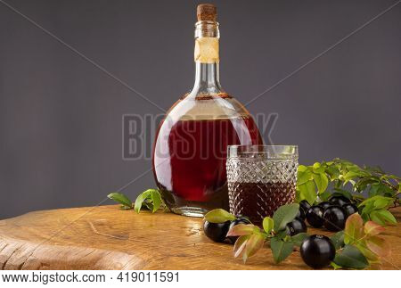Jaboticaba, Bottle And Glass Of Homemade Brazilian Jaboticaba Liqueur On Wood With Leaves And Branch