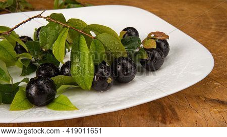 Jabuticaba, Jabuticabas In Detail Inside A White Plate With Branches And Leaves On Rustic Wood, Sele