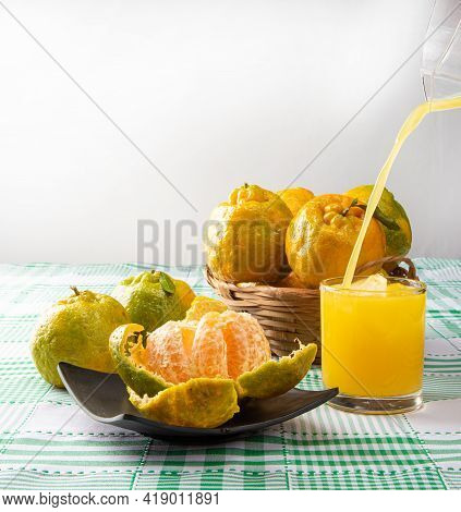 Orange Ponkan, Orange Ponkan Open On A Black Plate, Plus Some Oranges And A Glass Of Juice On A Chec