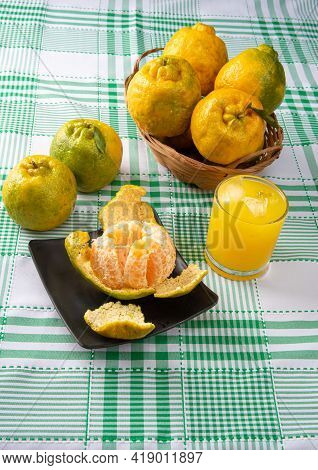 Orange Ponkan, Orange Ponkan Open On A Black Plate, Plus Some Oranges And A Glass Of Juice On A Chec