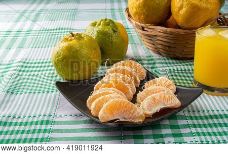 Orange Ponkan, Orange Ponkan Slices On A Black Plate, Plus Some Oranges And A Glass Of Juice On A Ch