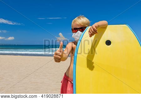 Young Surfer Boy With Body Board Wearing Sunglasses, Protective Masks On Sea Beach. Summer Tours, Cr