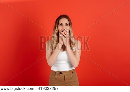 Young Woman Over Isolated Red Background Covering Mouth With Hands