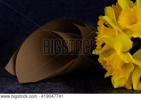 A Partially Visible Bouquet Of Narcissuses Is Lying Beside A Paper Cone