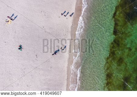 Spring Beach. Transparent Sea Water. Seaweed. People On The Sand. View From The Drone.