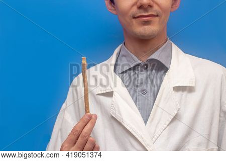 A Young Man Holds A Miswak Siwak In A White Coat. Arak Tree, Salvadora Persica, Sunnah. Blue Backgro