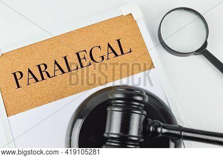 Phrase Paralegal Written On Brown Board With Judge Gavel And Magnifying Glass.
