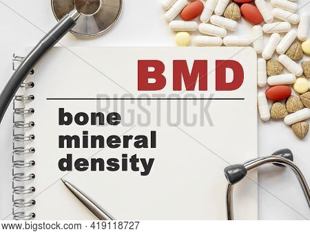 Page In Notebook With Bmd Bone Mineral Density On White Background With Stethoscope And Group Of Pil