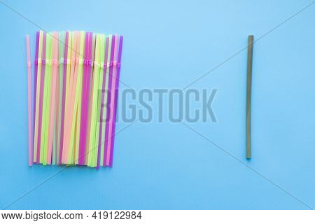 Many Plastic Drinking Straws Vs One Reusable Bamboo Drinking Straw On A Blue Background. Zero Waste 
