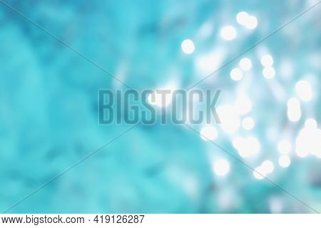 Background Of Blurred Blue Water With Sun Reflection