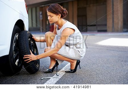 businesswoman in the city with flat tire frustrated