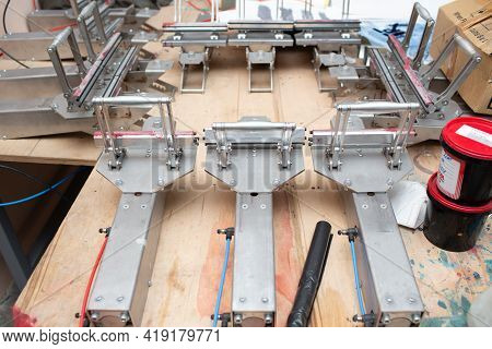 Serigraphy Silk Screen Print Process At Clothes Factory. Tensioner Frame, Squeegee And Plastisol Col