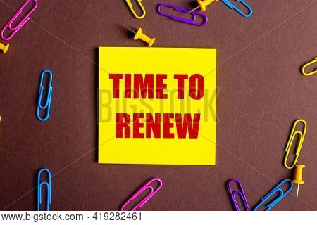 The Words Time To Renew Is Written In Red On A Yellow Sticker On A Brown Background Next To Multi-co