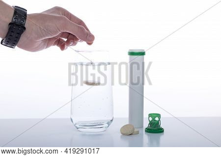 Throw The Pill Into A Glass Of Water. Throw Vitamins Into Water. Hand Throwing A Pill. Front View.