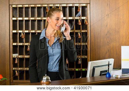 Receptionen på hotel, desk clerk, kvinde tager et opkald og smilende