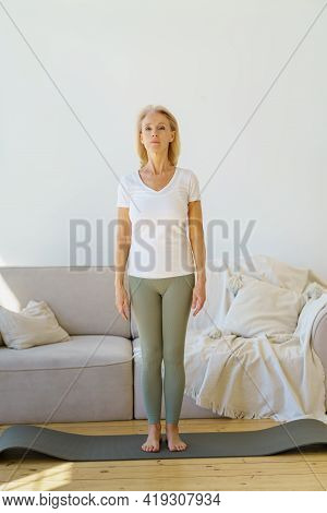 Active Lifestyle On Retirement. Calm Focused Senior Woman In Home Wear Standing In Mountain Pose On 