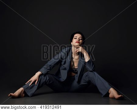 Self-confident Powerful Brunette Businesswoman In Official Suit On Naked Body Sits On Floor With Leg