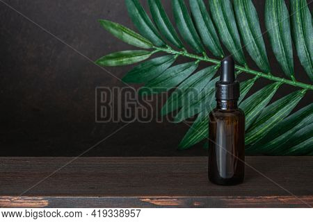 Bottle Of Oil, Essential On Wooden Table And Dark Borwn Background. Concept Of Aroma Oil, Ingredient