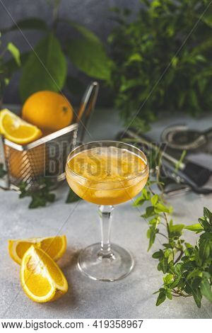Champagne Coupe Glass Of Refreshing Orange Cocktail With Ice Served On Gray Table Surface Surround O
