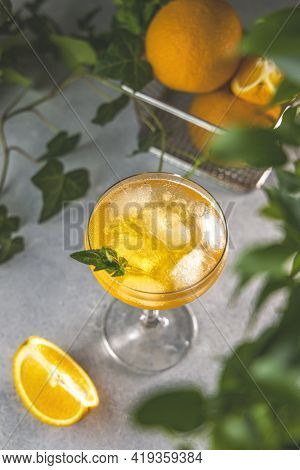 Champagne Coupe Glass Of Refreshing Orange Cocktail With Ice Served On Gray Table Surface Surround O