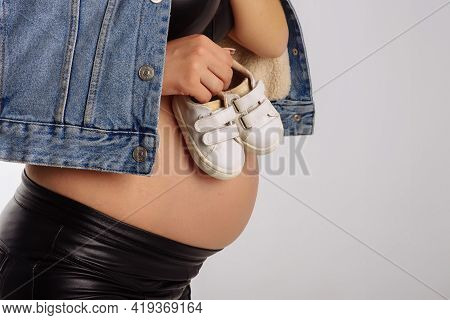 Small Shoes For Unborn Baby In The Belly Of A Pregnant Woman