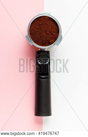 Espresso Machine Filte Holder With Ground Coffee On Pink And White Background.