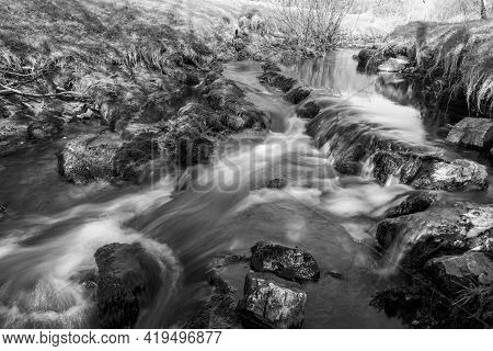Long Exposure Of The Weir Water River  Flowing Through The Valley At Robbers Bridge In Exmoor Nation