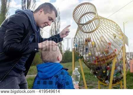 Dad And Son Throw The Plastic Bottle Into The Plastic Collection Container. Recycling And Disposal O