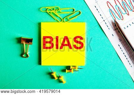 The Word Bias Is Written In Red On A Yellow Sticker On A Green Background Near The Graph And Pencil