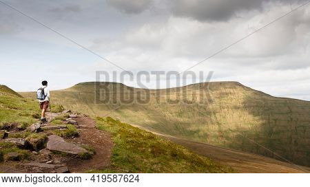 Asian Indian Woman Hiking Alone In Welsh Hills, Looking Towards Pen Y Fan, Brecon Beacons, Wales, Uk