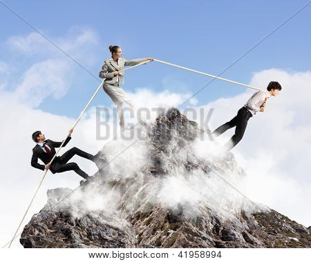 Imagem de três empresários puxando a corda no topo da montanha