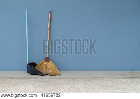 Broom And Dustpan Old On The Blue Cement Wall