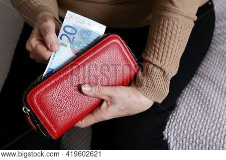 Elderly Woman Takes Out A Euro Note From Her Wallet. Concept Of Pension Payments, Savings At Retirem