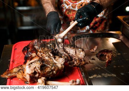 Chev Cuts Juicy Cooked Meat, Separating The Meat From The Bone With A Knife.
