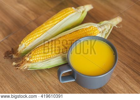 A Cup Of Warm Corn Soup Beside With Fresh Ear Of Corn Lay Down On The Table. Corn Is A Healthy Food 