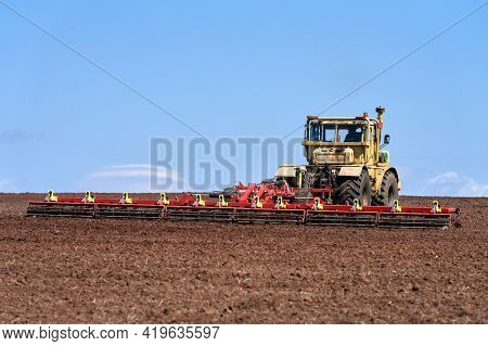 Seasonal Agricultural Work In The Field. Heavy Tractor With Harrow Close-up. Copy Space.